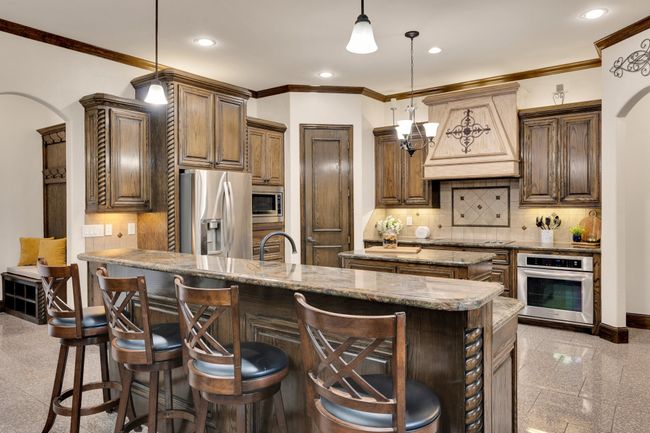 Kitchen featuring crown molding, stainless steel appliances, a kitchen island, and custom range hood | Image 11