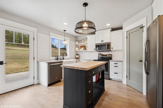 Kitchen with butcher block countertops, white cabinets, open shelves, and stainless steel appliances | Image 12