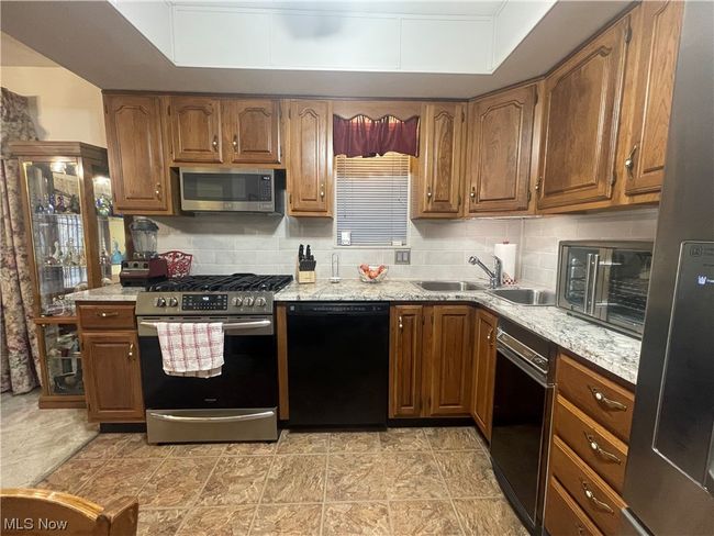 Kitchen with light tile floors, stainless steel appliances, backsplash, and sink | Image 10