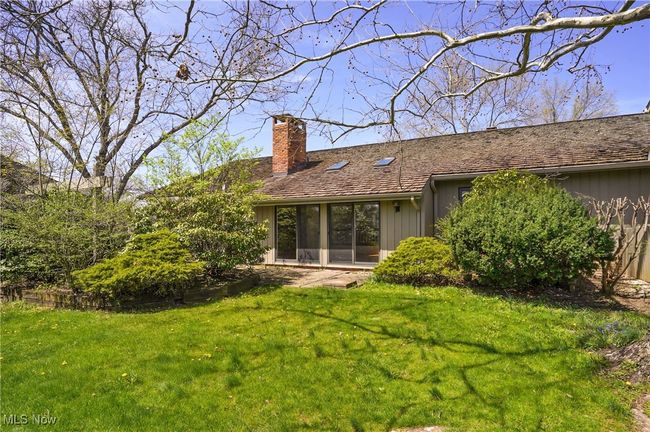 Rear view of property with board and batten siding, a lawn, and a chimney | Image 12