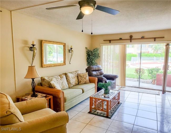 Living room with a textured ceiling, ceiling fan, and light tile patterned flooring | Image 6