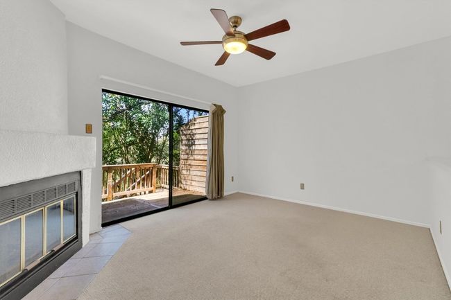 Unfurnished living room with a ceiling fan, light carpet, baseboards, and a fireplace | Image 12