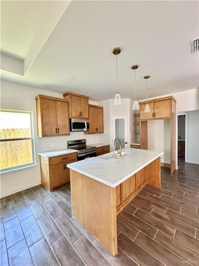 Kitchen featuring a sink, stainless steel appliances, brown cabinetry, and wood tiled floor | Image 5