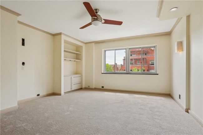 Bedroom with built-ins, a ceiling fan, baseboards, light carpet, and ornamental molding | Image 8
