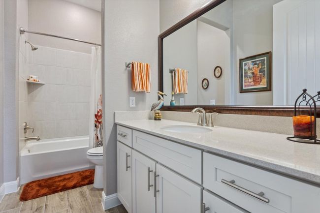 En Suite Bathroom featuring vanity, framed mirror, shower / bath combo, and wood look tile flooring | Image 25