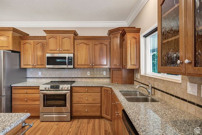 Kitchen featuring stainless steel appliances, a sink, brown cabinets, and crown molding | Image 9