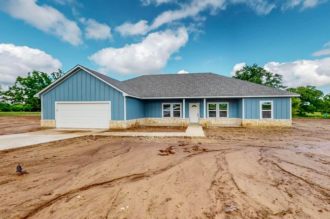 Ranch-style home featuring a shingled roof, a garage, concrete driveway, and stone siding | Image 5