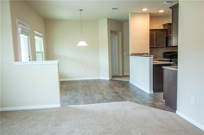 Kitchen featuring black range oven, dark brown cabinetry, light carpet, pendant lighting, and recessed lighting | Image 17