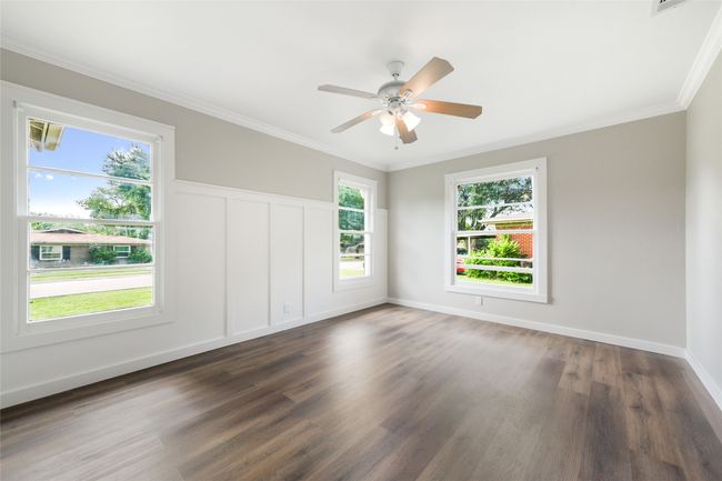 Empty room featuring dark wood-type flooring, ornamental molding, plenty of natural light, and ceiling fan | Image 26