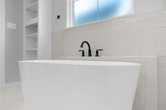 Bathroom featuring tile walls, tile patterned flooring, a washtub, and a wealth of natural light | Image 18
