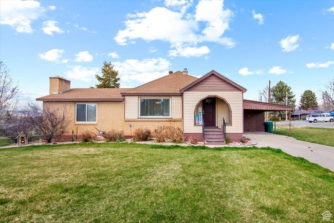 View of front of house featuring a chimney, an attached carport, brick siding, a front lawn, and driveway | Image 12