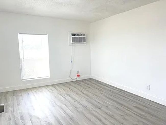 Empty room featuring wood finished floors, a textured ceiling, and a wall mounted AC | Image 7
