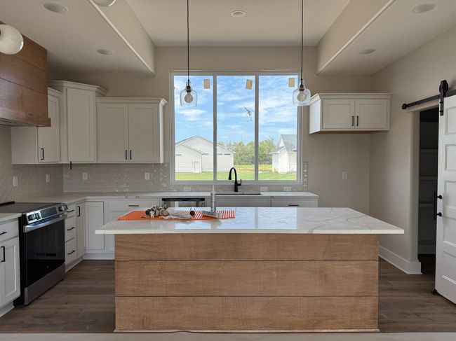 Kitchen with stainless steel appliances, a barn door, white cabinetry, dark wood-style flooring, and recessed lighting | Image 7