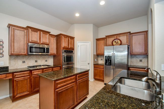 Spacious kitchen with cherry wood cabinets, granite countertops, and stainless steel appliances. Features a central island, double ovens, and a built-in microwave. | Image 13