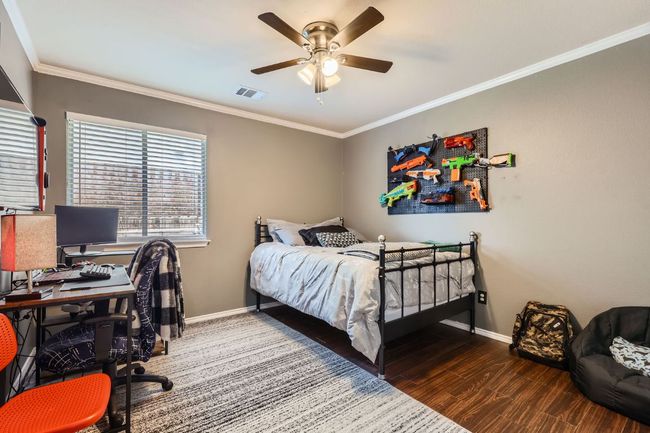 Bedroom with ornamental molding, wood finished floors, an office area, and ceiling fan | Image 17