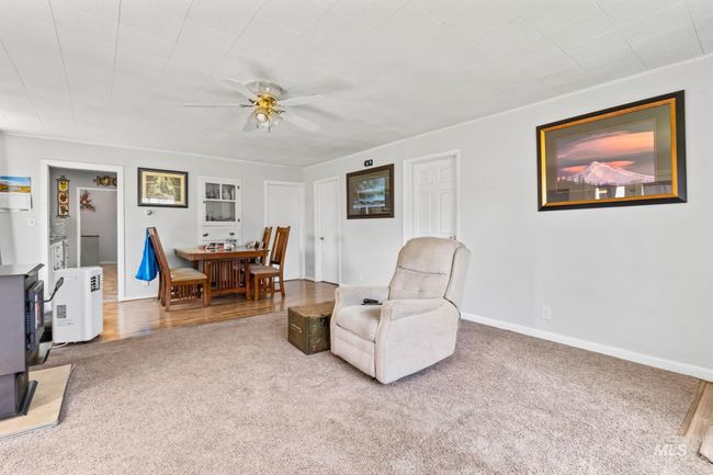 Living area featuring carpet flooring, ceiling fan, and a wood stove | Image 6