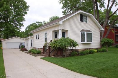 View of front of property with an outdoor structure, a garage, and a front lawn | Image 1