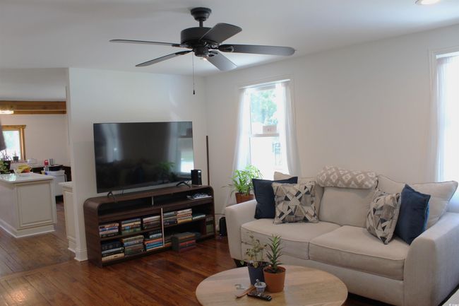 Living area featuring healthy amount of natural light, wood finished floors, and a ceiling fan | Image 7