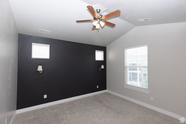 Carpeted empty room with lofted ceiling, ceiling fan, and baseboards | Image 11