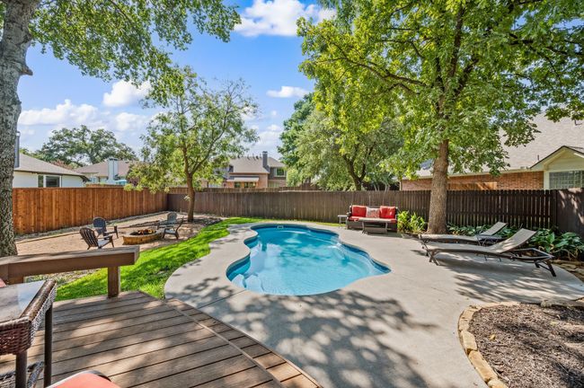 View of swimming pool with a patio area, a fenced backyard, an outdoor living space with a fire pit, and a wooden deck | Image 30