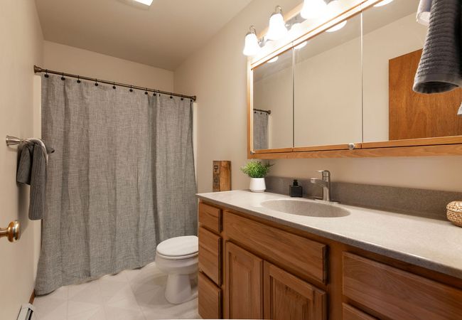 Bathroom with baseboard heating, vanity, and curtained shower | Image 15
