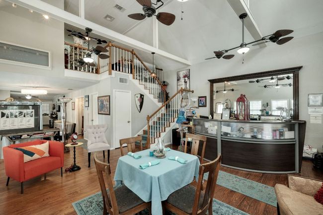 Dining area with ceiling fan, high vaulted ceiling, wood finished floors, and stairway | Image 10