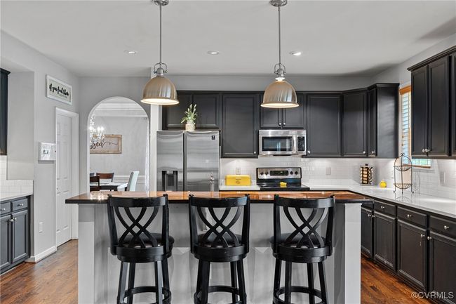 Kitchen featuring tasteful backsplash, dark wood-style flooring, appliances with stainless steel finishes, and a kitchen island | Image 13