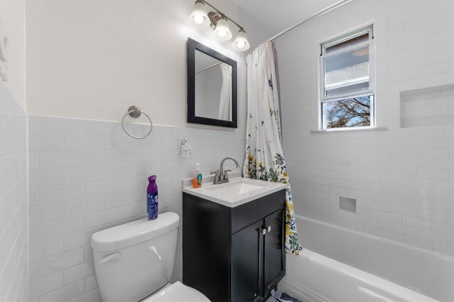 Full bathroom featuring shower / bath combo, toilet, vanity, and tile walls | Image 25