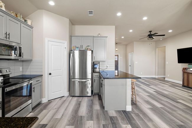 Kitchen featuring light wood-style flooring, a peninsula, a breakfast bar area, and appliances with stainless steel finishes | Image 14