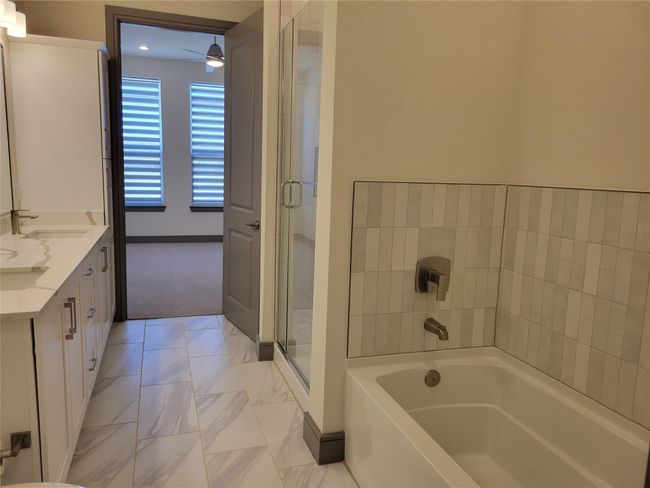 Bathroom featuring a garden tub, baseboards, a sink, and double vanity | Image 13
