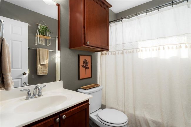 Bathroom with toilet, vanity, and curtained shower | Image 20