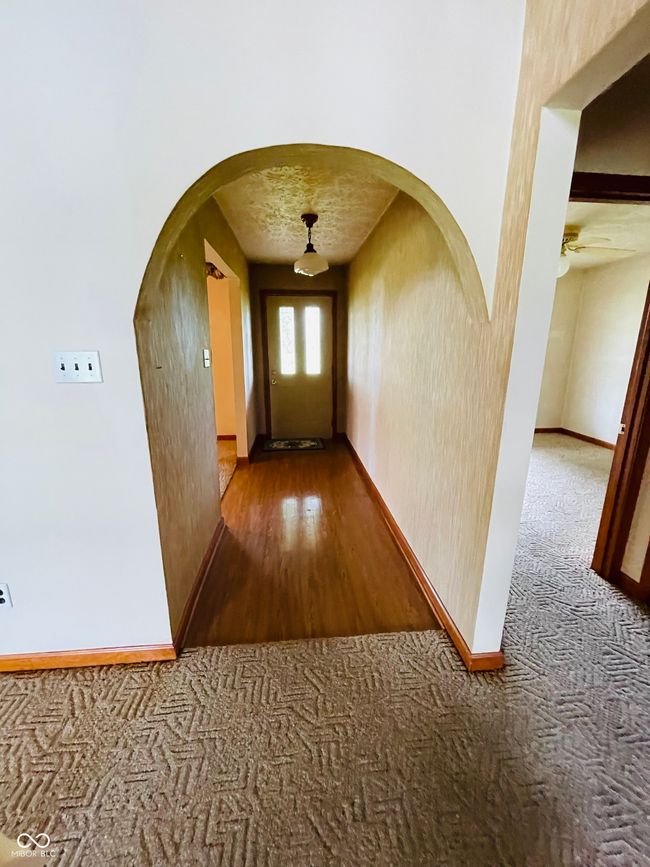 hallway featuring baseboards, arched walkways, carpet floors, and wood finished floors | Image 14