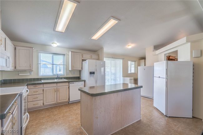 Kitchen with white appliances, a sink, dark countertops, and healthy amount of natural light | Image 13