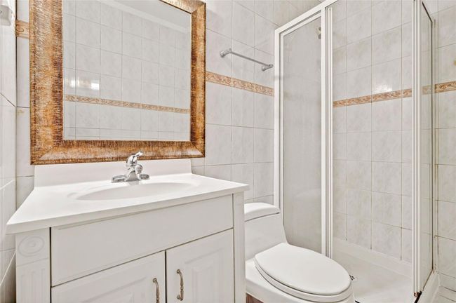 Bathroom with a shower stall, toilet, tile walls, and vanity | Image 44