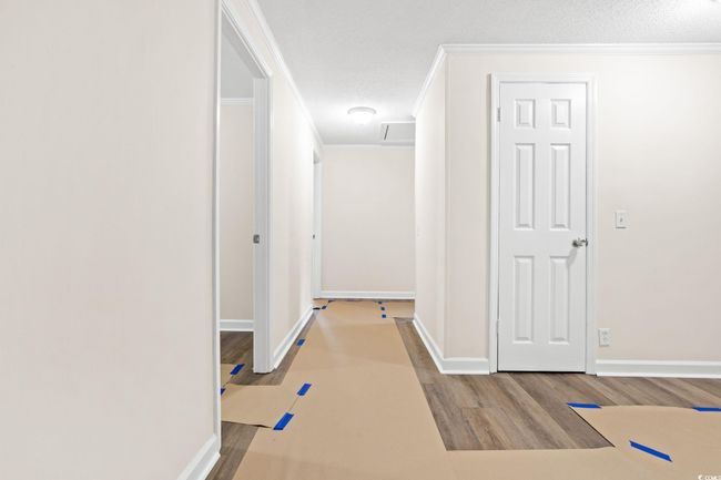 Corridor featuring wood finished floors, crown molding, baseboards, and a textured ceiling | Image 27