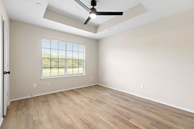 Spare room featuring a raised ceiling, light wood-style floors, baseboards, and ceiling fan | Image 23
