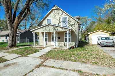 View of front facade featuring an outbuilding, covered porch, a front yard, and a garage | Image 1