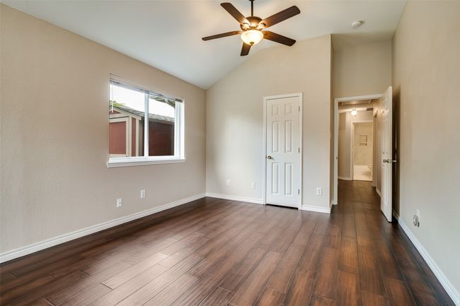 Unfurnished bedroom with vaulted ceiling, dark wood finished floors, a closet, and a ceiling fan | Image 24