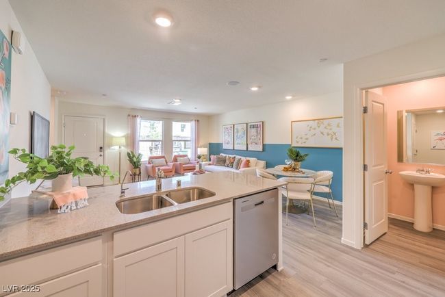 Kitchen featuring light stone countertops, a sink, dishwasher, white cabinets, and open floor plan | Image 16