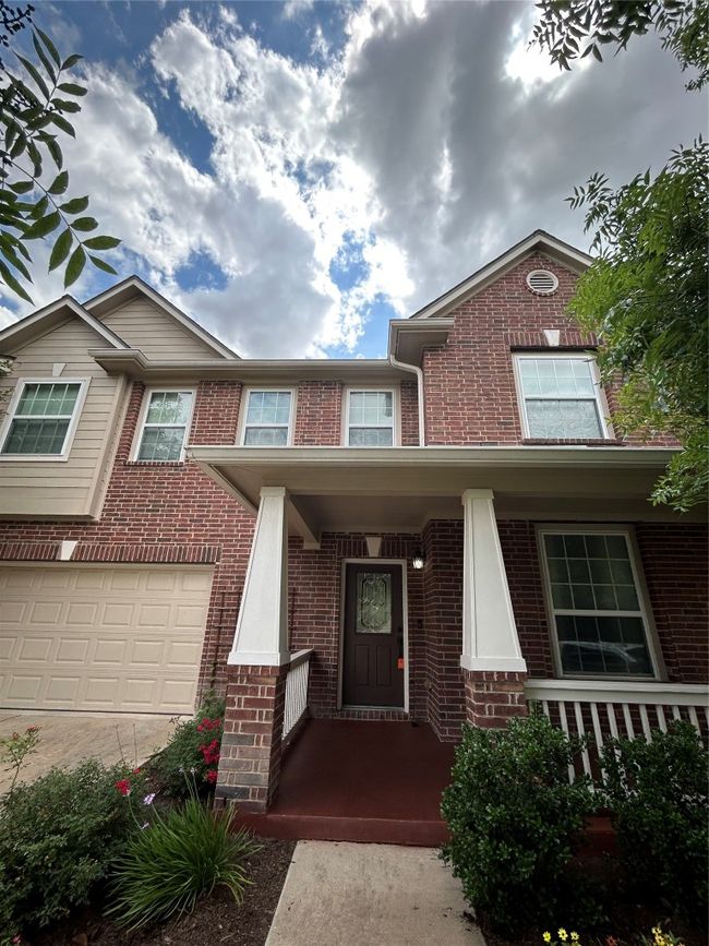 Doorway to property with brick siding, an attached garage, a porch, and concrete driveway | Image 4