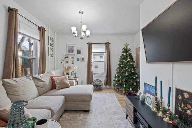 Living room with light hardwood / wood-style floors and a notable chandelier | Image 5