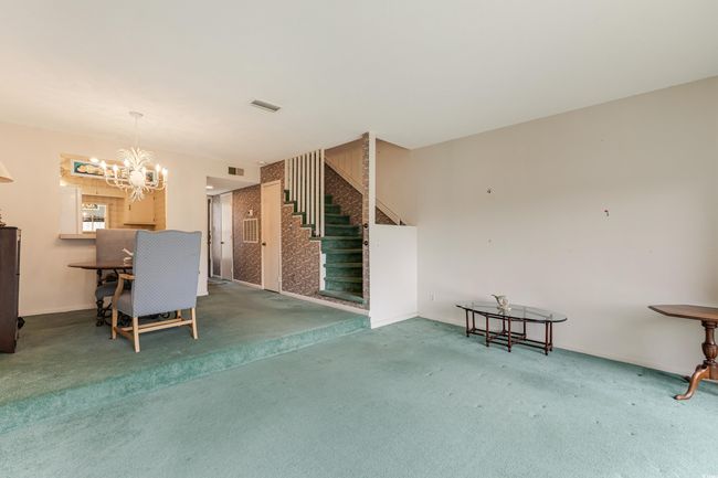 Interior space featuring stairs, a notable chandelier, visible vents, and carpet | Image 16