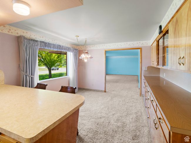 Kitchen with light carpet, a chandelier, wallpapered walls, and decorative light fixtures | Image 11