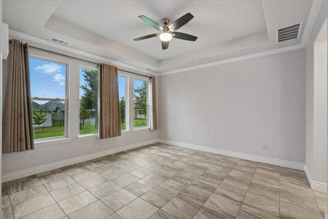 Primary bedroom with a tray ceiling, a ceiling fan, baseboards, and tile flooring | Image 13