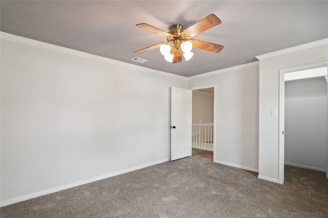 One of the secondary bedrooms, next to the primary bedroom, shows the fabulous walk-in closet, ceiling fan and crown molding. | Image 27
