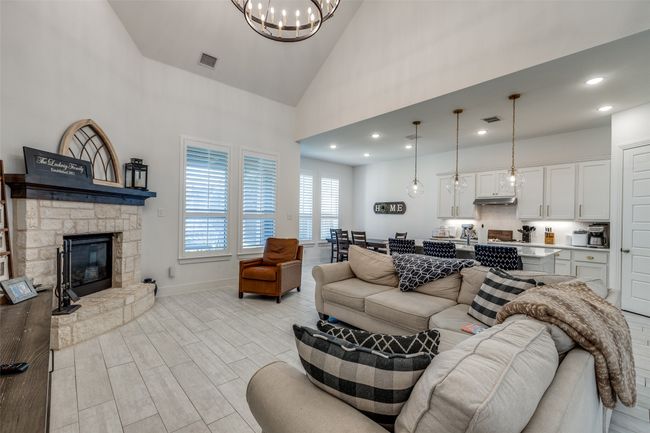 Living area featuring a fireplace, visible vents, high vaulted ceiling, and a notable chandelier | Image 7