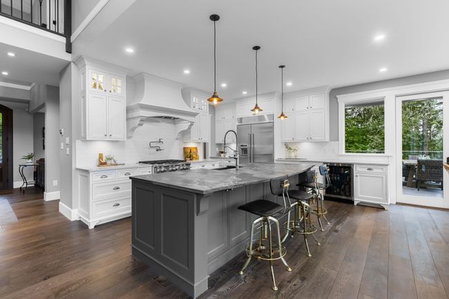 Kitchen featuring built in refrigerator, premium range hood, wine cooler, dark wood-style flooring, and white cabinets | Image 11