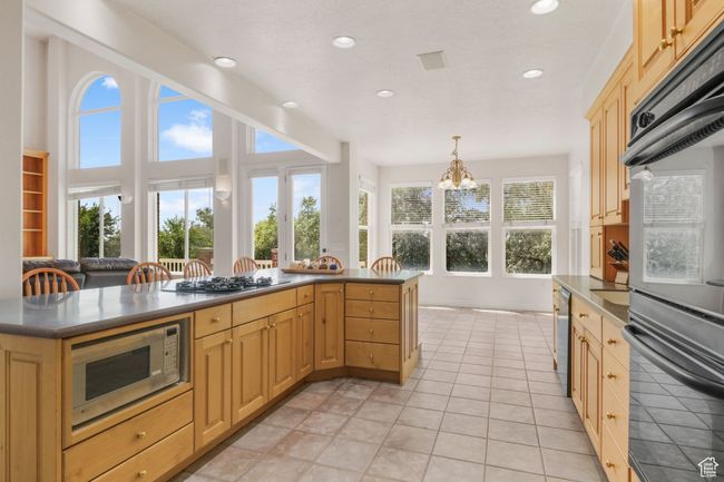 Kitchen with dark countertops, a notable chandelier, stainless steel appliances, and light brown cabinets | Image 6