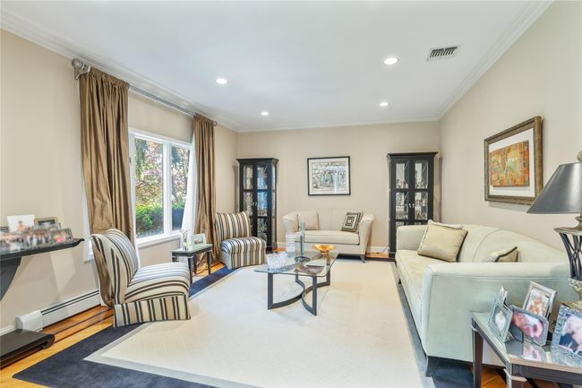 Living room with recessed lighting, ornamental molding, wood finished floors, a baseboard radiator, and baseboards | Image 7