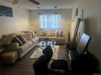 Living room featuring wood walls, ceiling fan, and dark hardwood / wood-style flooring | Image 2